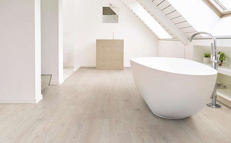 light luxury vinyl plank flooring in bathroom with white bathtub